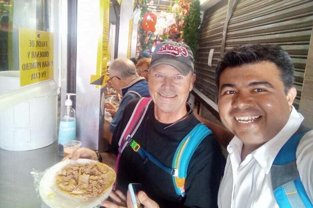 two men posing for a picture with a plate of food