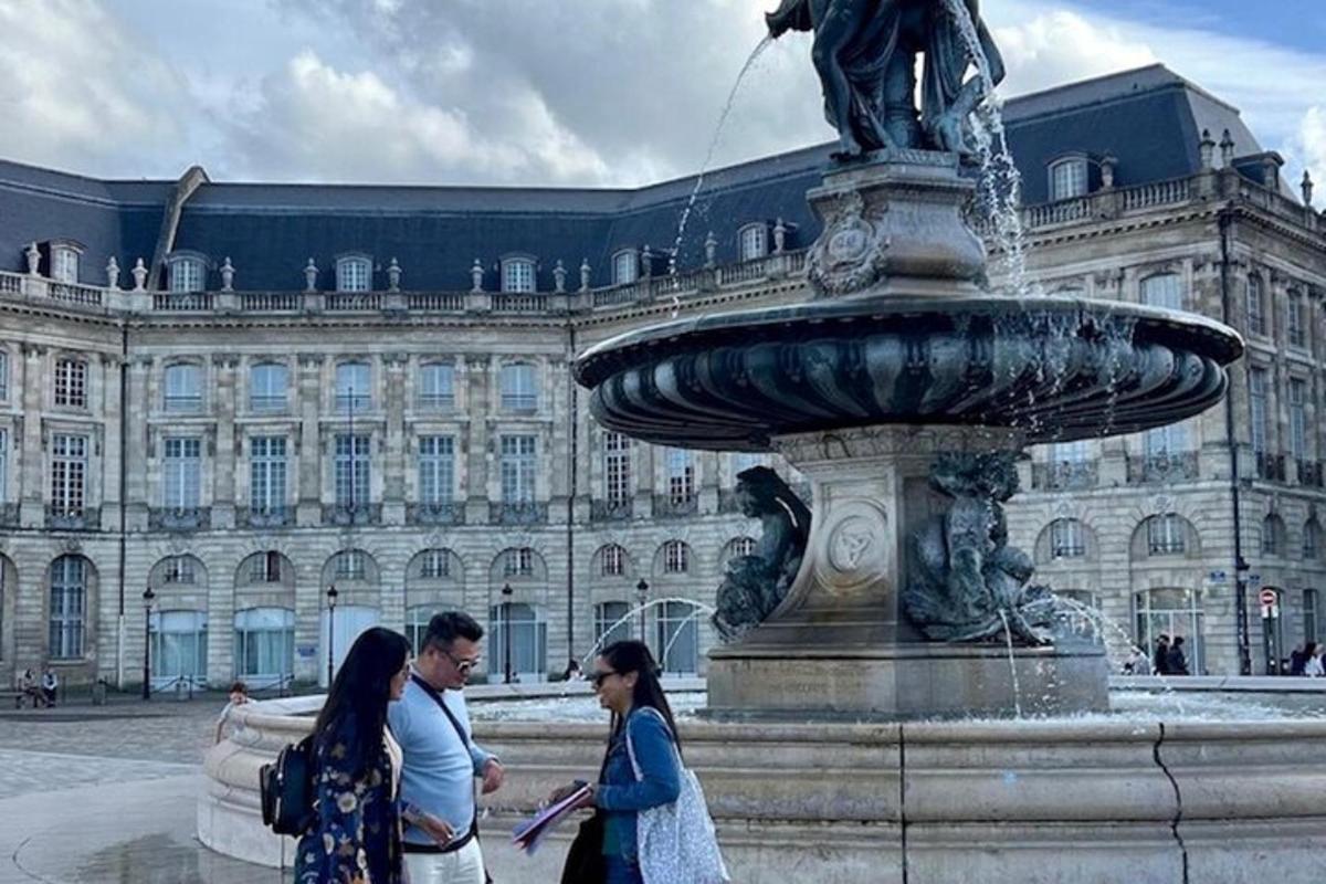 a group of people walking around a fountain in front of a building