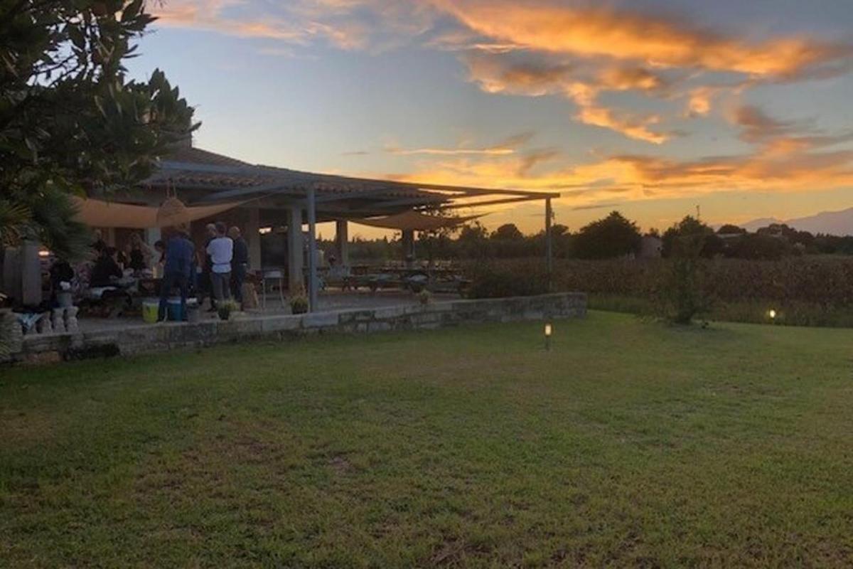 un grup de persones dempeus sota un pavelló a la posta de sol