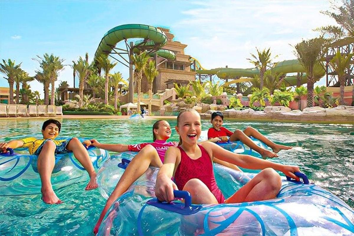 a group of children riding on inflatable tubes in the water at a resort