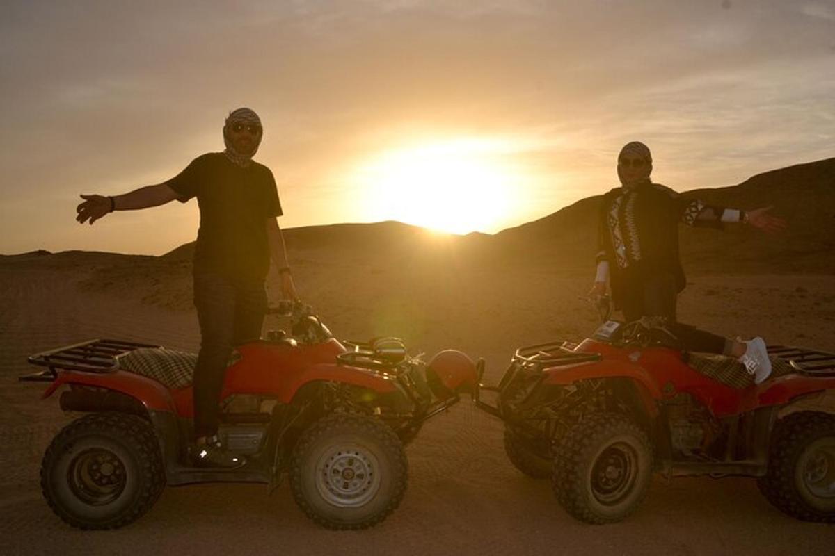 dua lelaki berdiri di atas atv di padang pasir pada waktu matahari terbenam