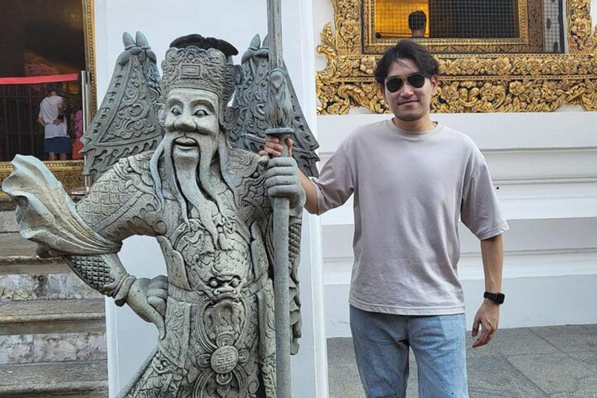 Ein Mann steht neben einer Statue vor einem Gebäude