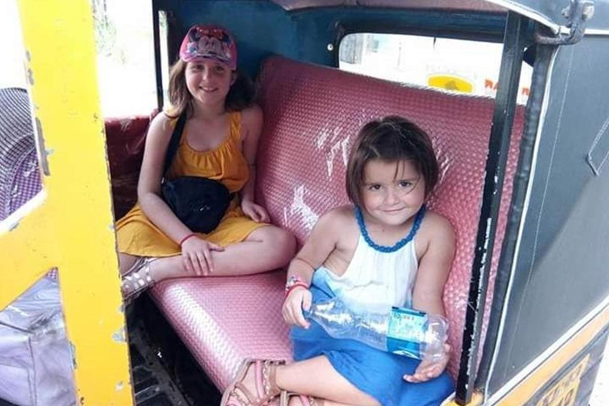 a young girl sitting on a pink chair with a little girl