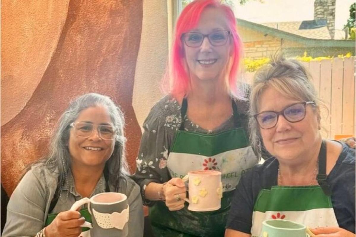 two women with pink hair holding coffee cups