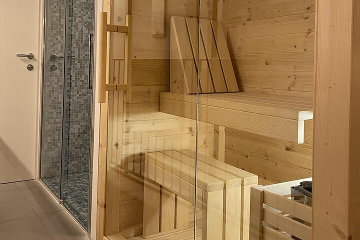 uma sauna de madeira com porta de vidro em um banheiro