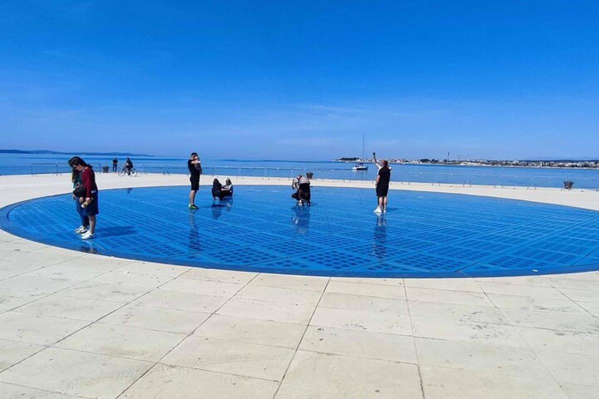 eine Gruppe von Menschen steht um einen blauen Kreis am Strand