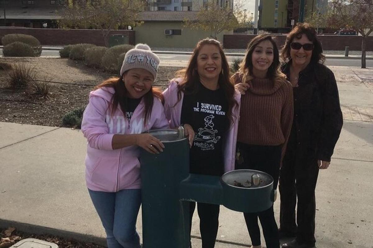 a group of girls standing next to a trash can