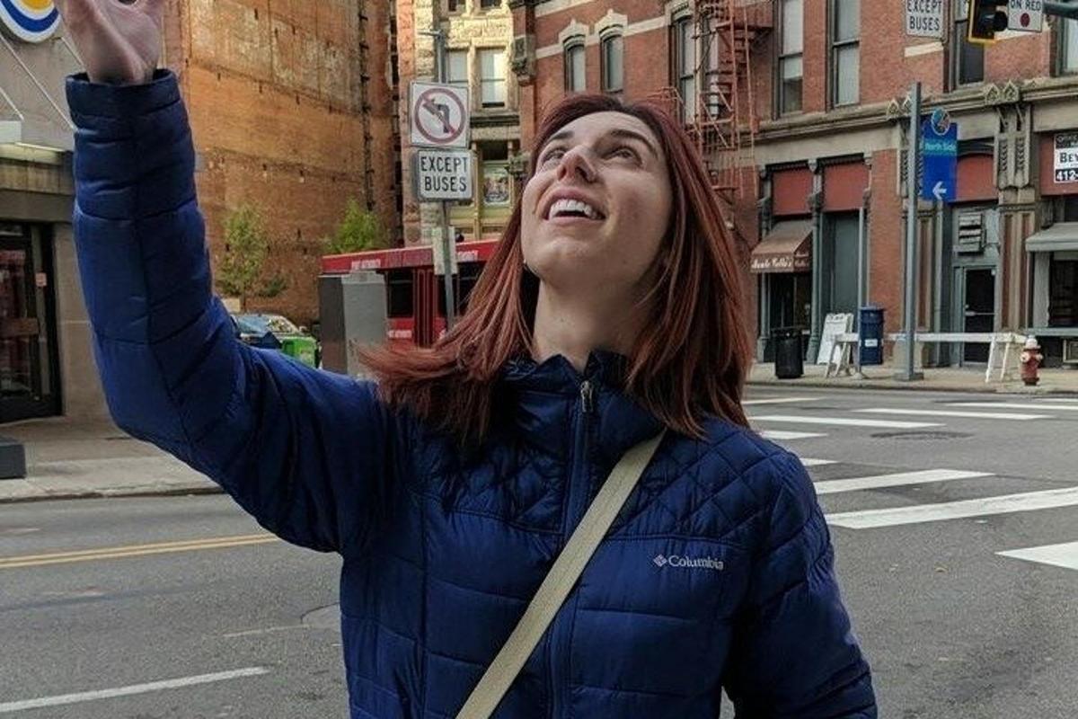 a woman is standing on a street with her hand in the air