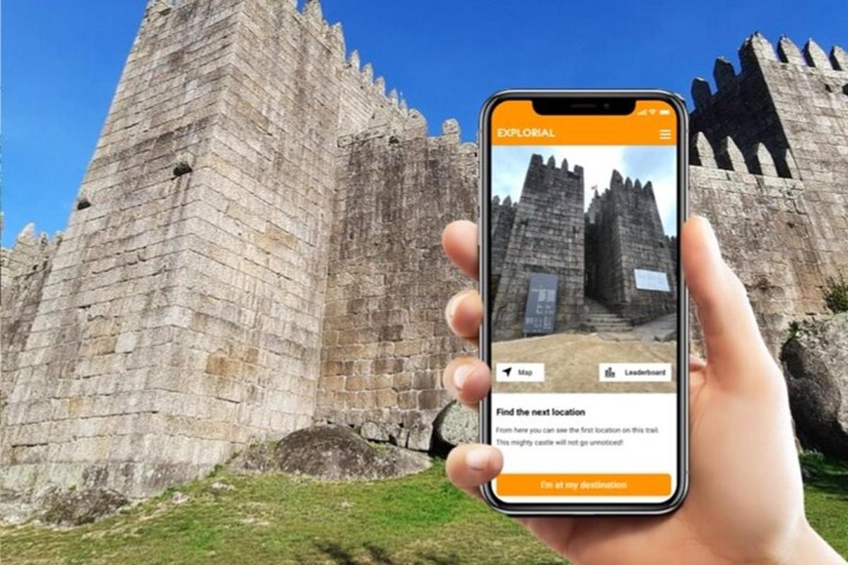 osoba držící mobilní telefon před hradem