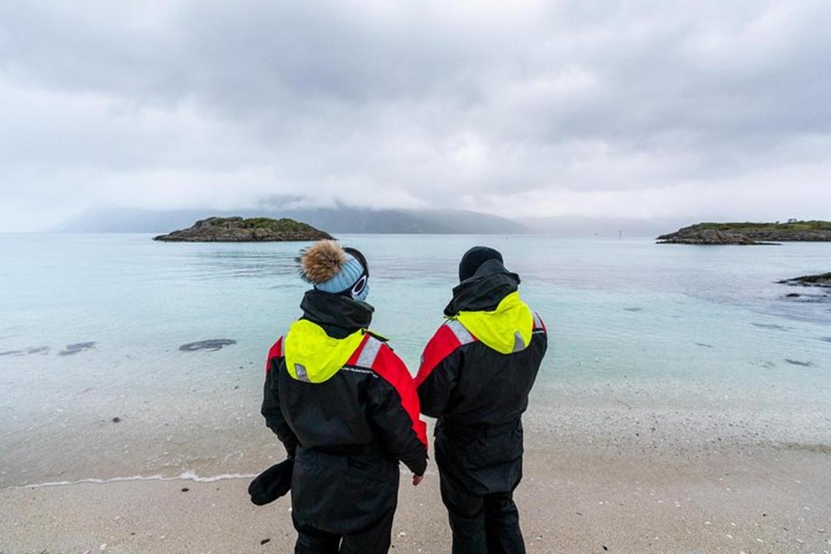 dva lidé stojící na pláži a dívající se na oceán