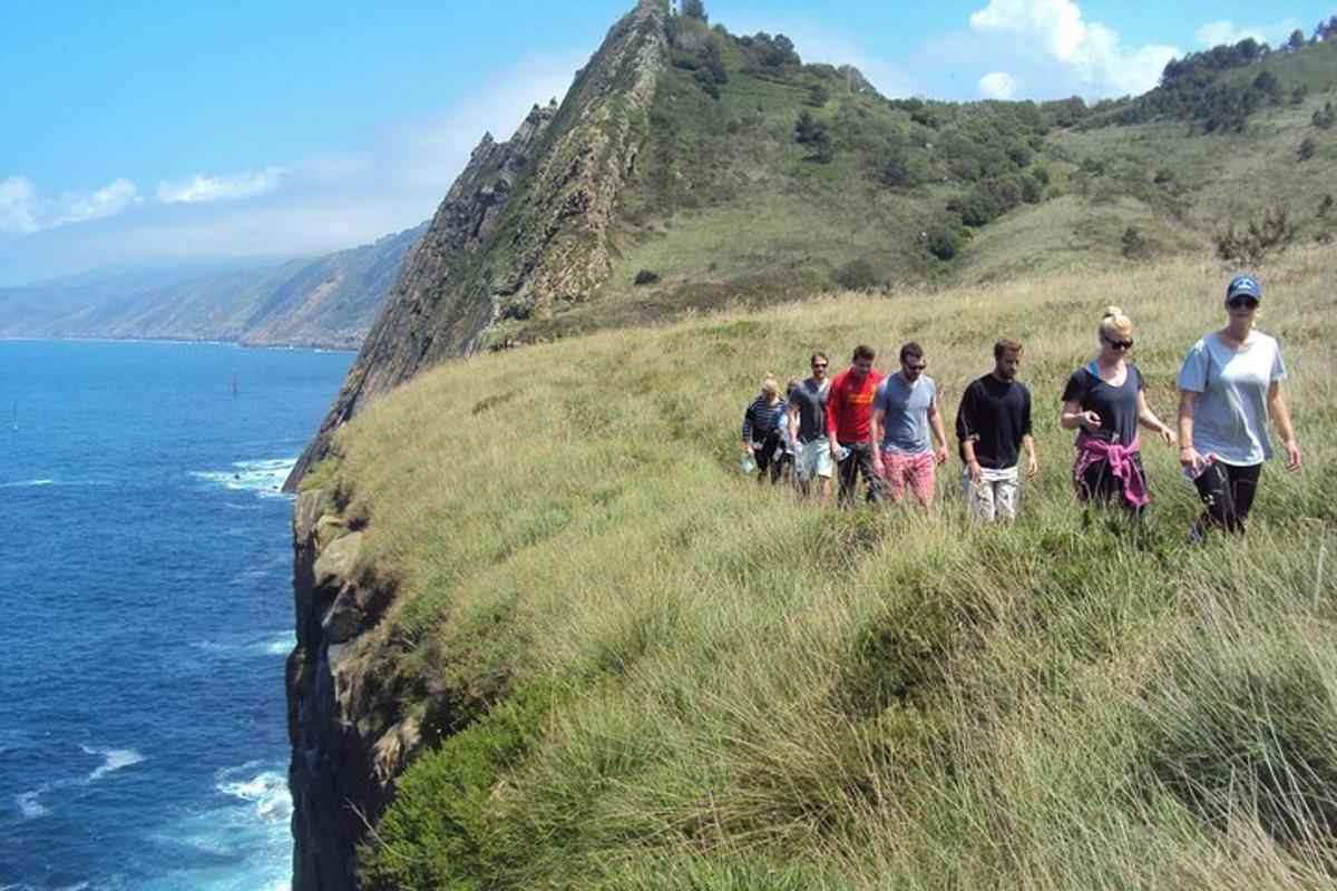 sekumpulan orang berjalan di atas bukit berhampiran lautan