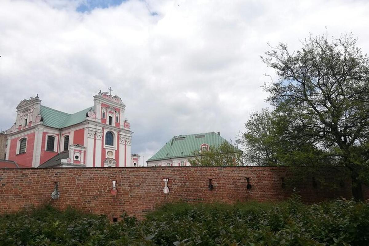růžová budova se zelenou střechou za cihlovou zdí