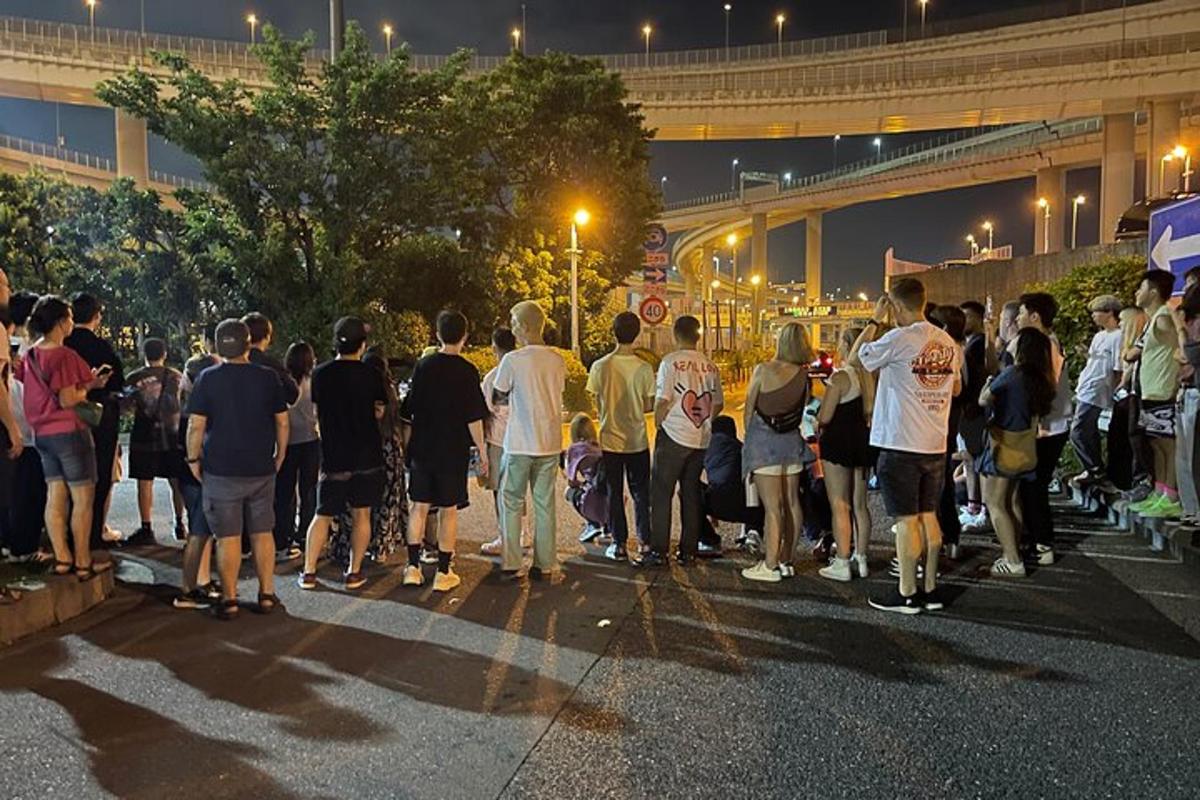 Un grupo de personas de pie entre una multitud en una calle.
