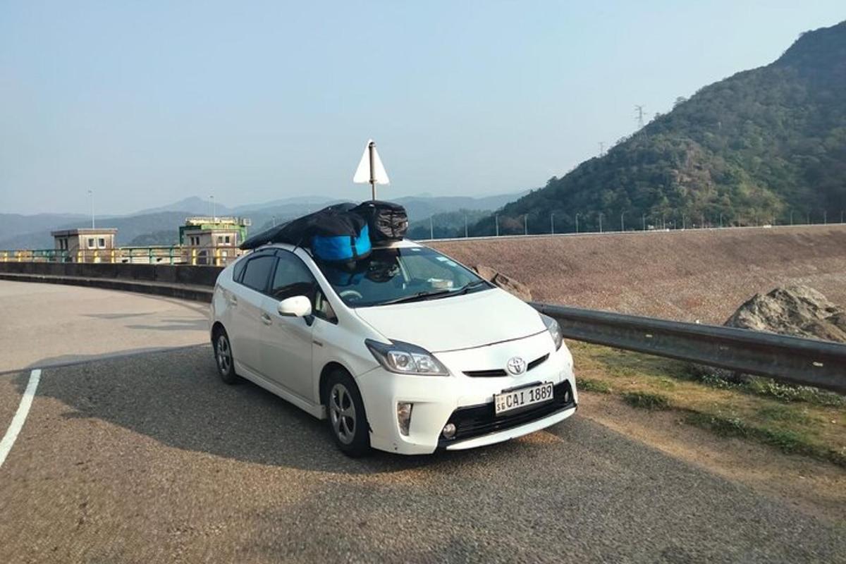 un home conduint un petit cotxe blanc per la carretera