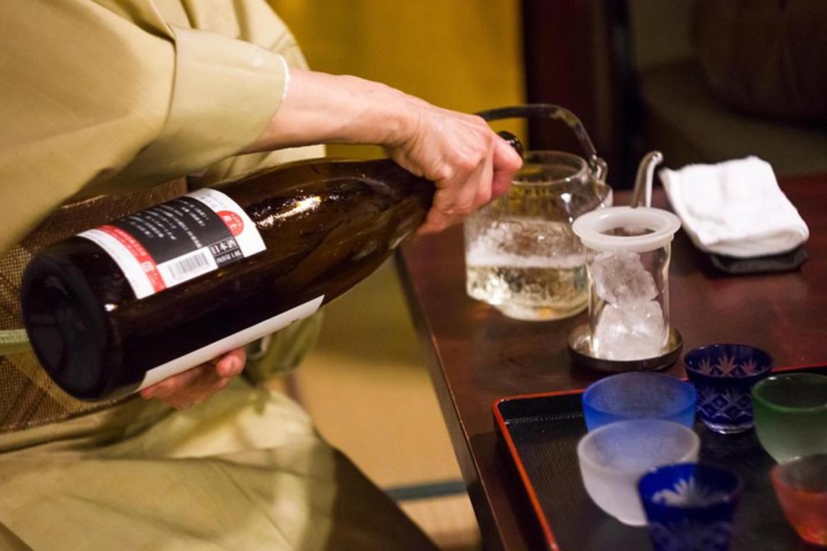en person som holder en flaske vin på et bord