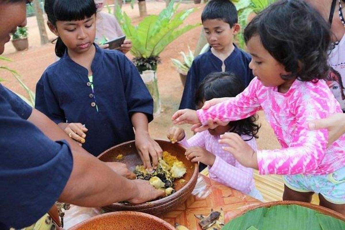 a group of children standing around a table eating food