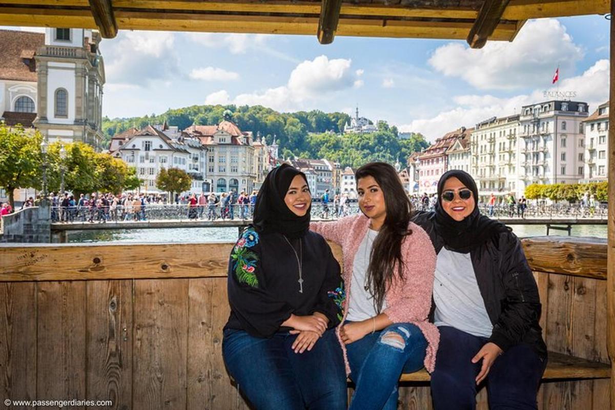Tres mujeres sentadas en una valla frente a un río