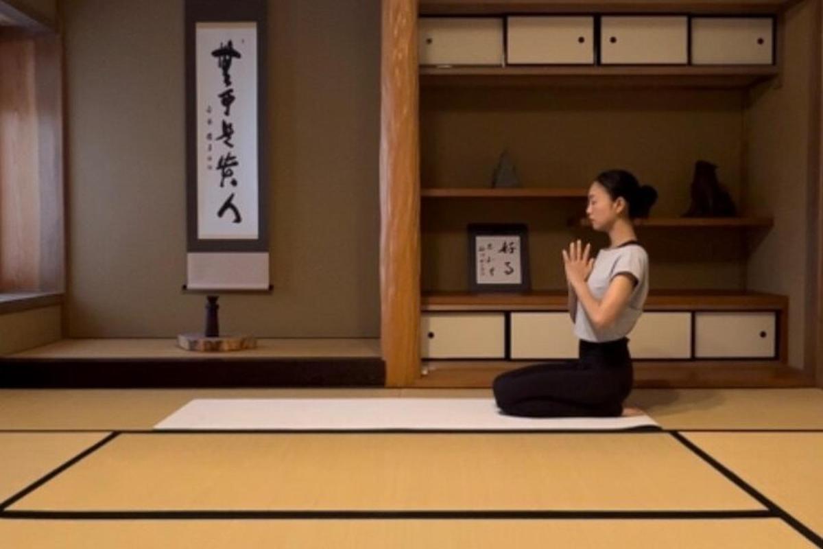 部屋の中で床に座ってヨガをしている女性