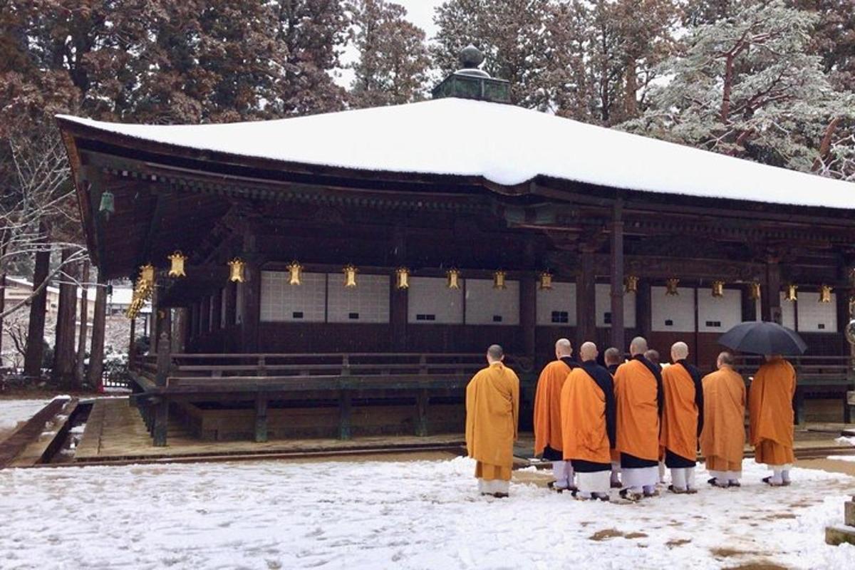 a group of monks standing in front of a building in the snow