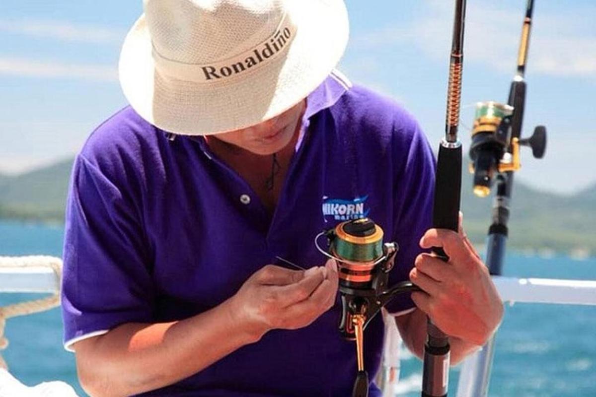muž v klobúku pozerá na fotoaparát s rybou
