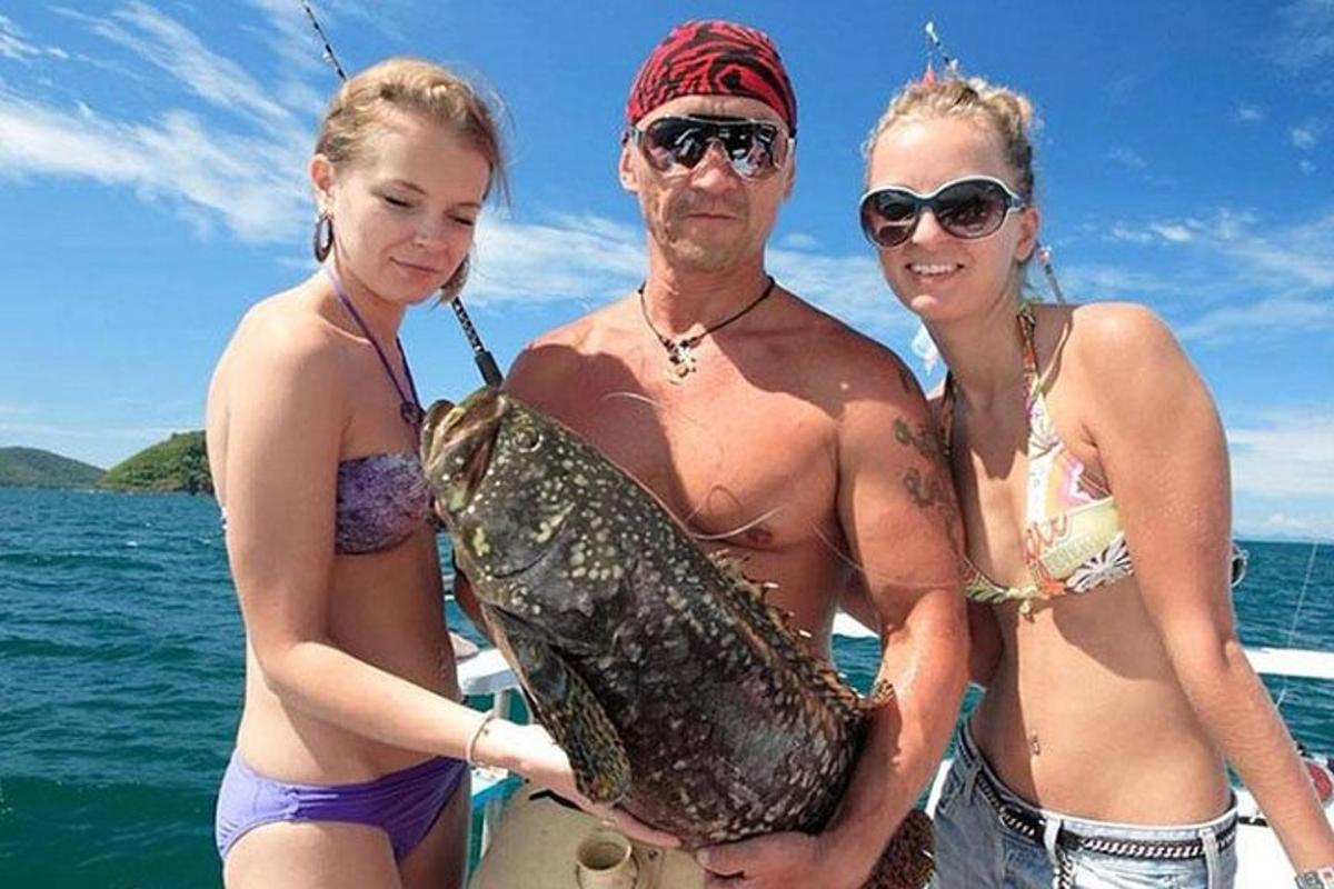 un uomo e due donne in piedi su una barca con un pesce