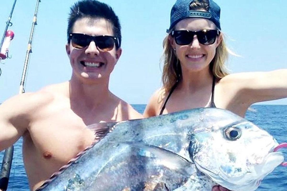 un uomo e una donna che tengono in mano un grosso pesce
