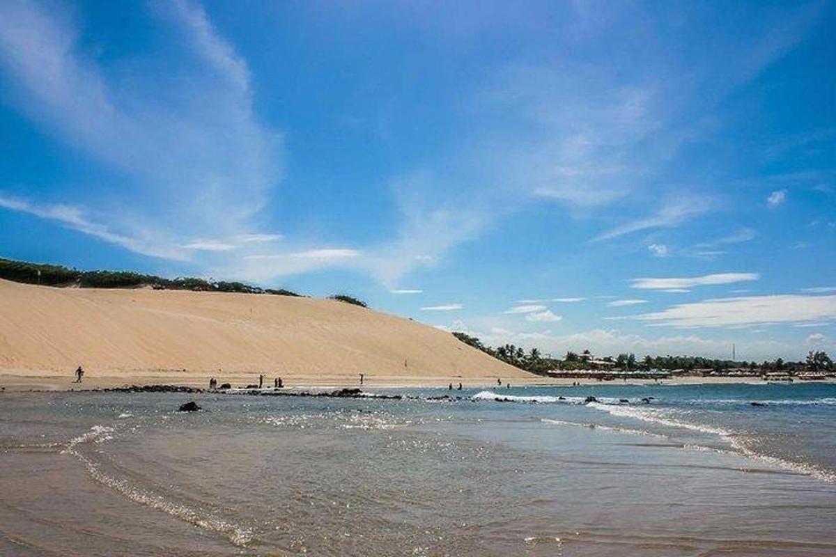 a beach with a large sand dune in the background