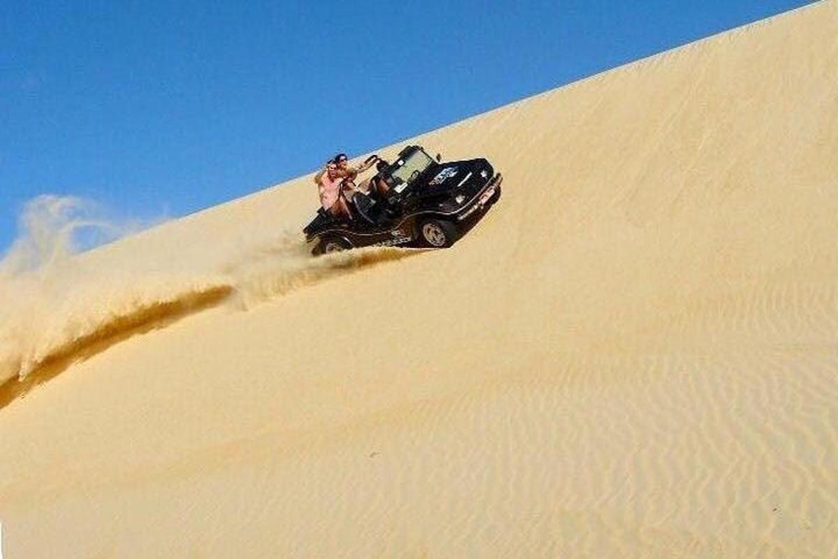 a group of people riding a atv on a sand dune