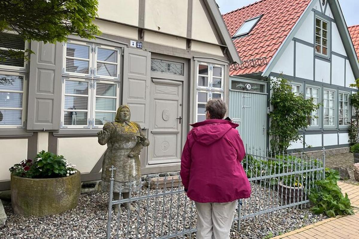 kona stendur við hlið styttu fyrir framan hús