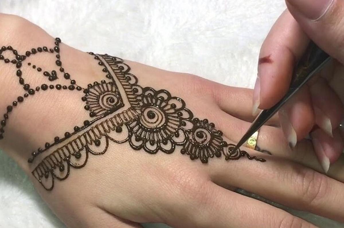 a woman is getting her henna tattoo on her back