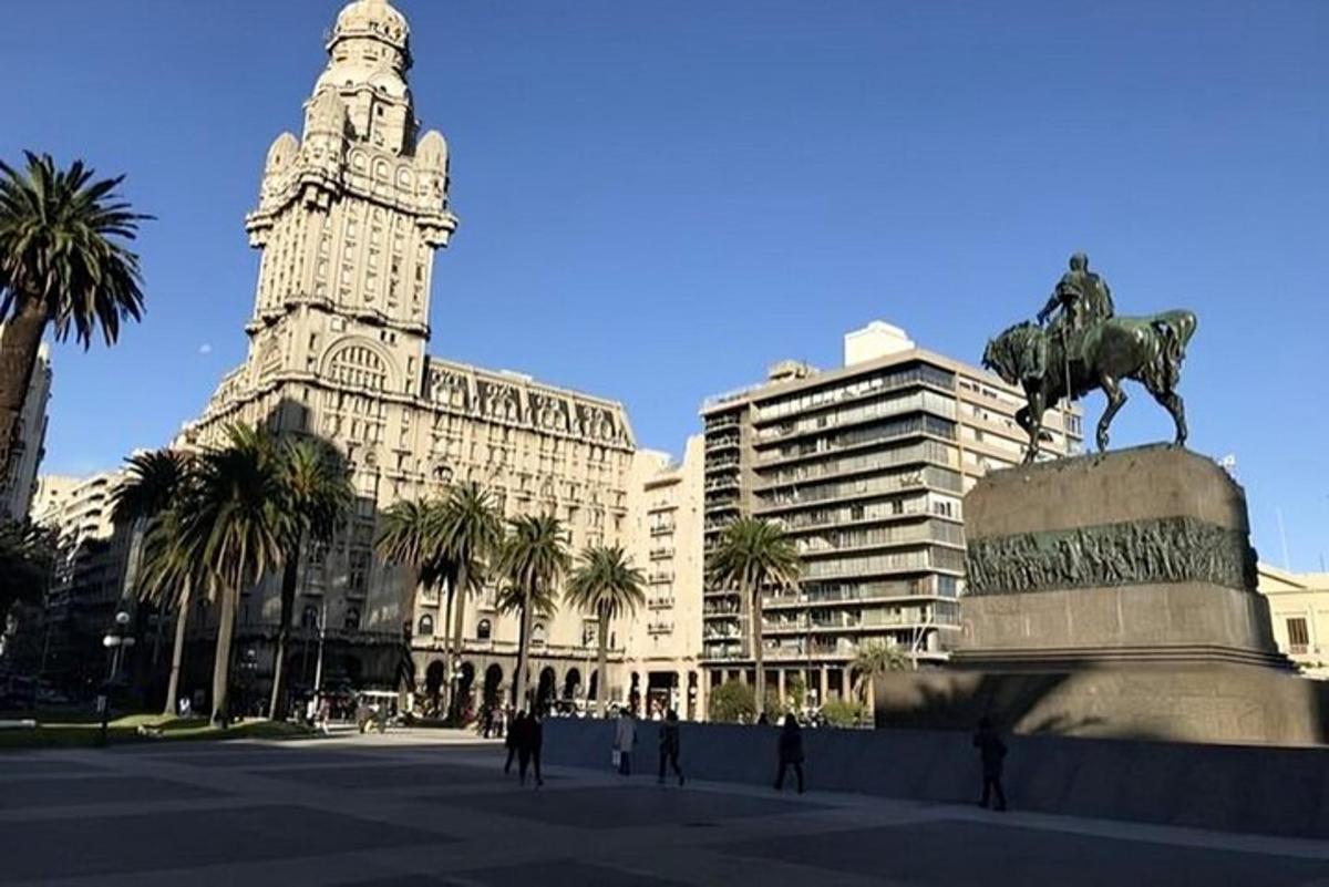 una estatua frente a un edificio con una torre de reloj
