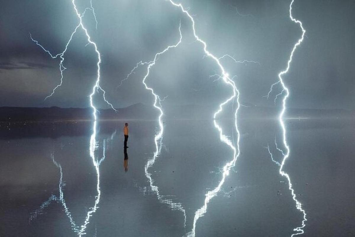a person standing in the middle of the water with lightning