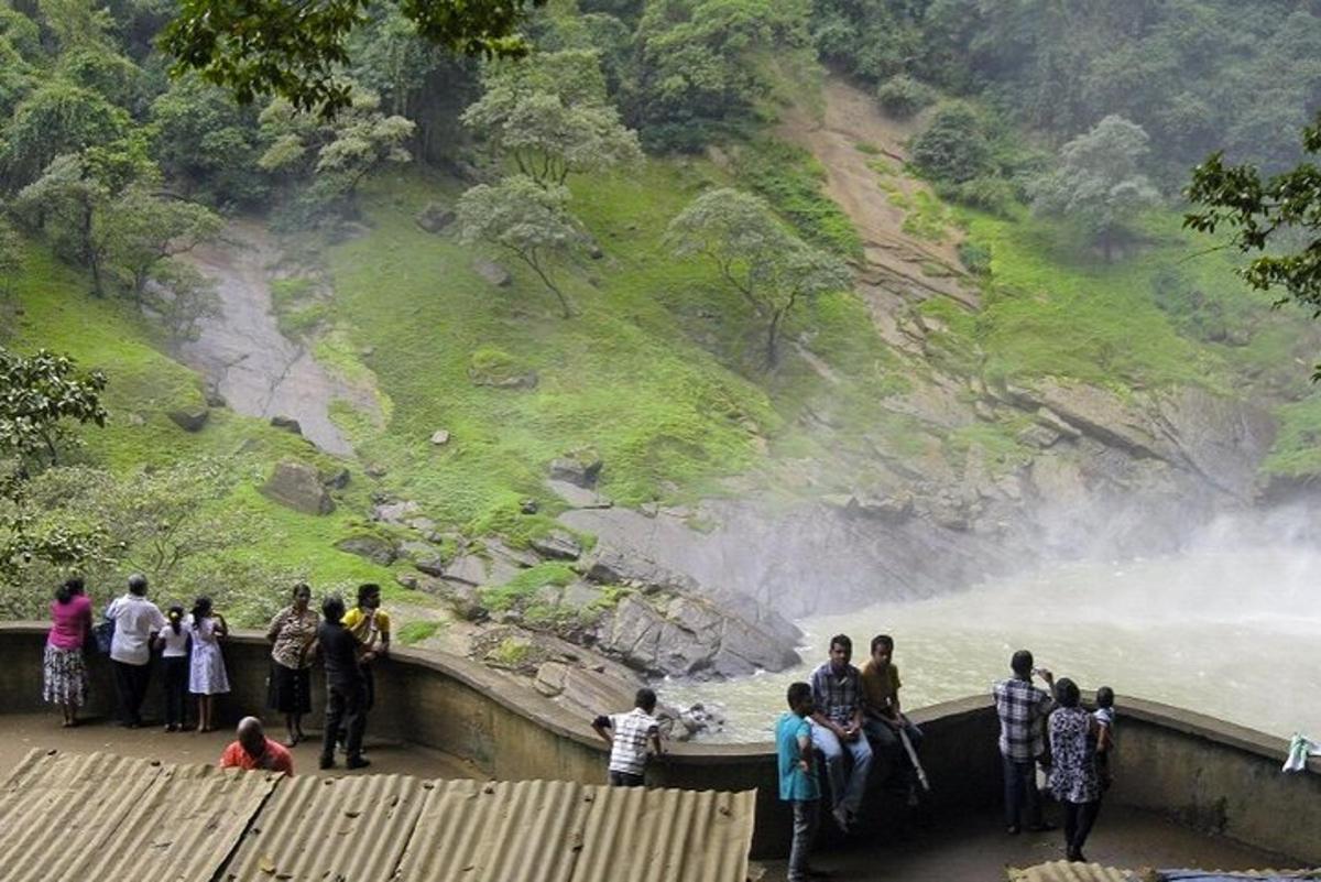 um grupo de pessoas em pé em uma ponte olhando para uma cachoeira