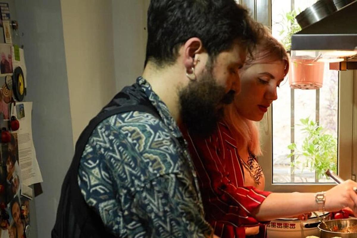 moški in ženska v kuhinji pripravljata hrano