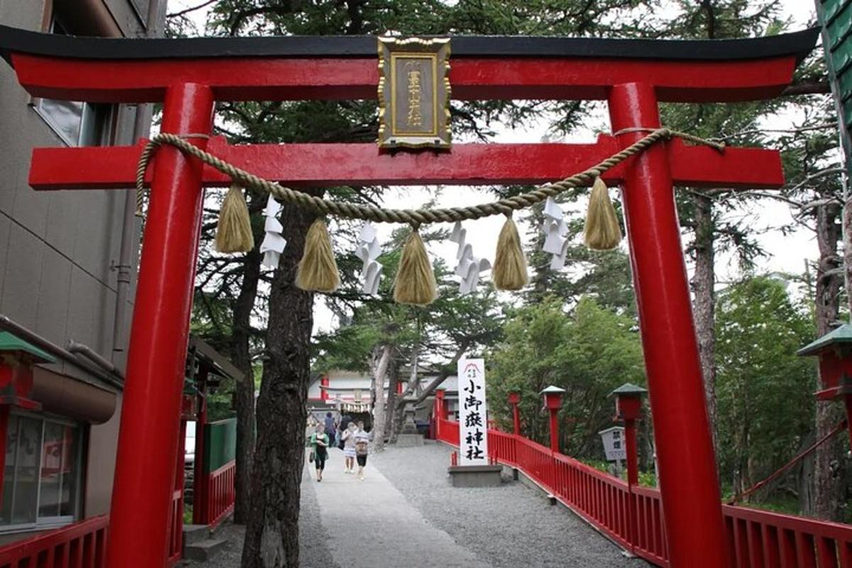 un cancello torii rosso in una strada con persone che camminano