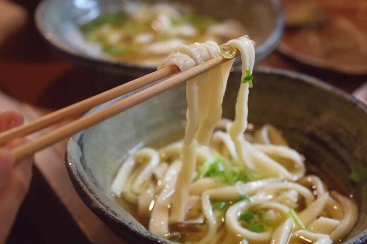 a person is eating a bowl of noodles with chopsticks