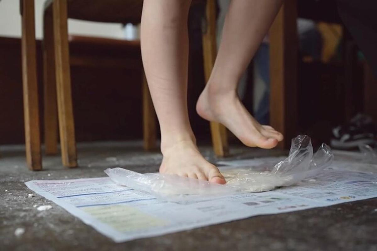 uma pessoa em pé sobre um pedaço de plástico no chão
