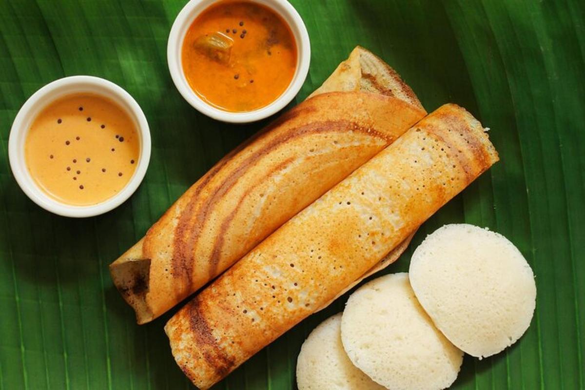 a green plate with bread and two bowls of dipping sauce