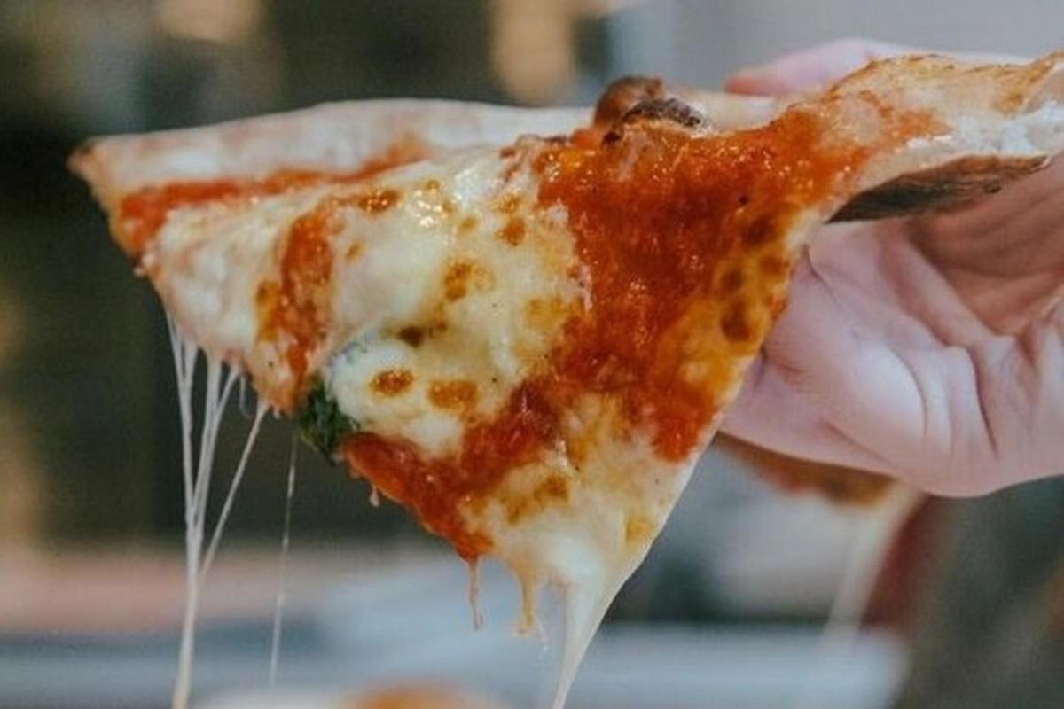 osoba drží kus pizzy