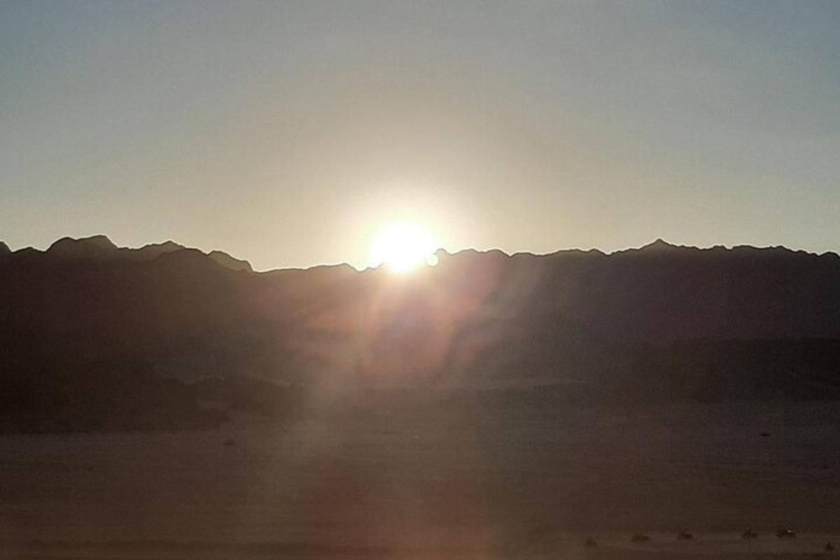 a sun is setting over a mountain range