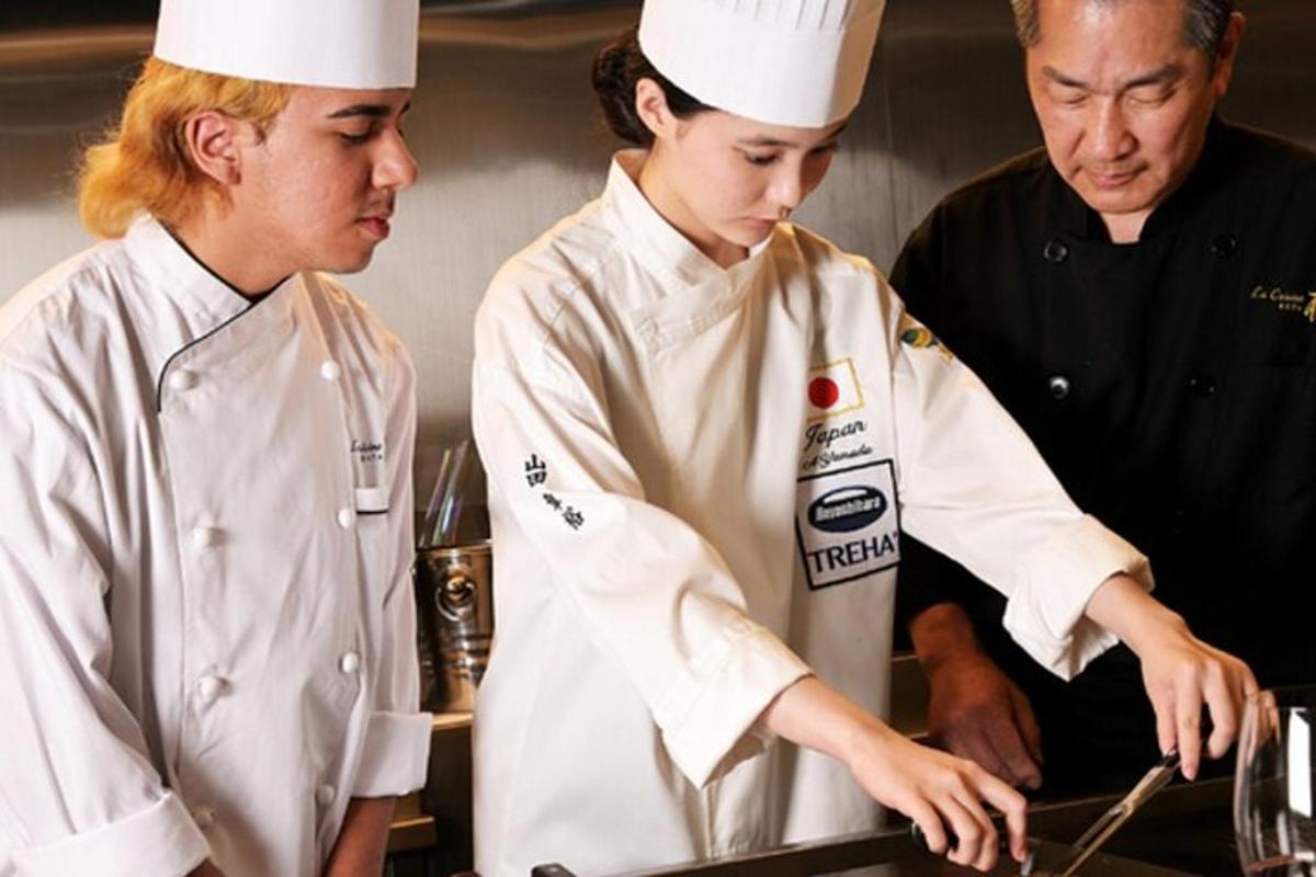 sekumpulan tiga chef menyediakan makanan di dapur