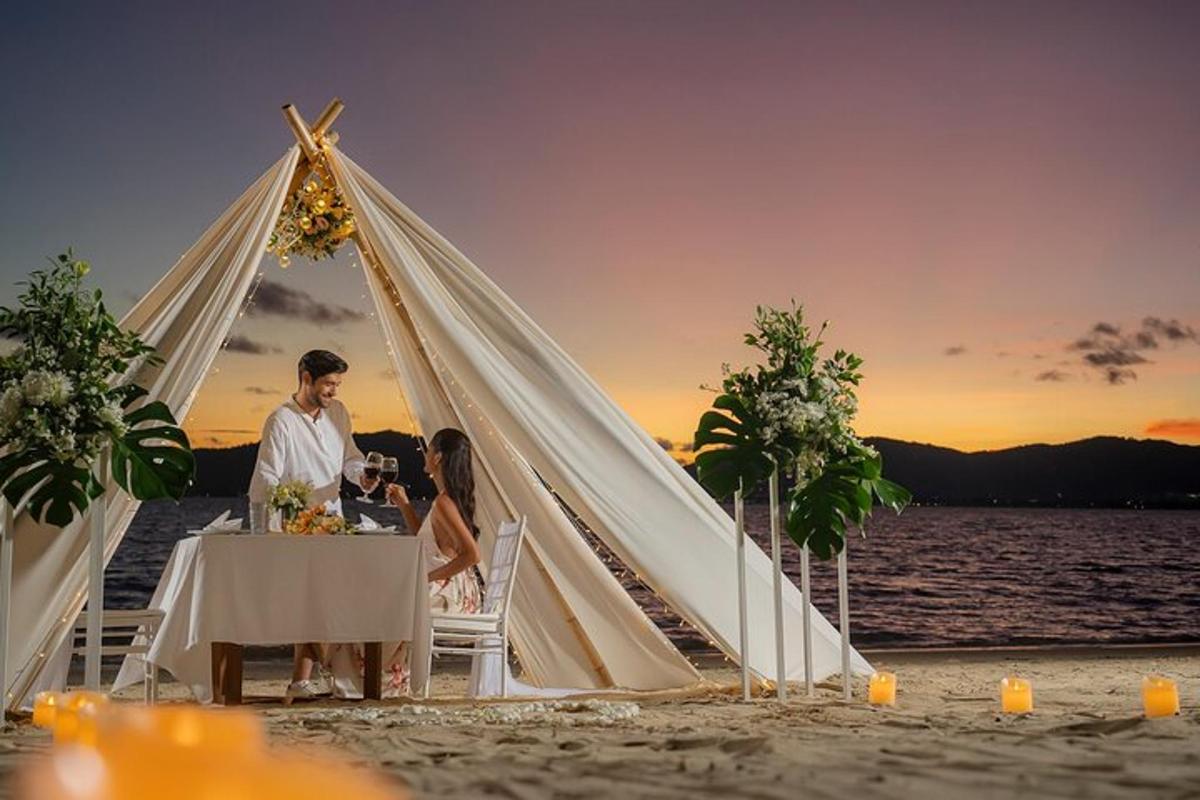 eine Hochzeitsgesellschaft sitzt an einem Tisch in einem Zelt am Strand