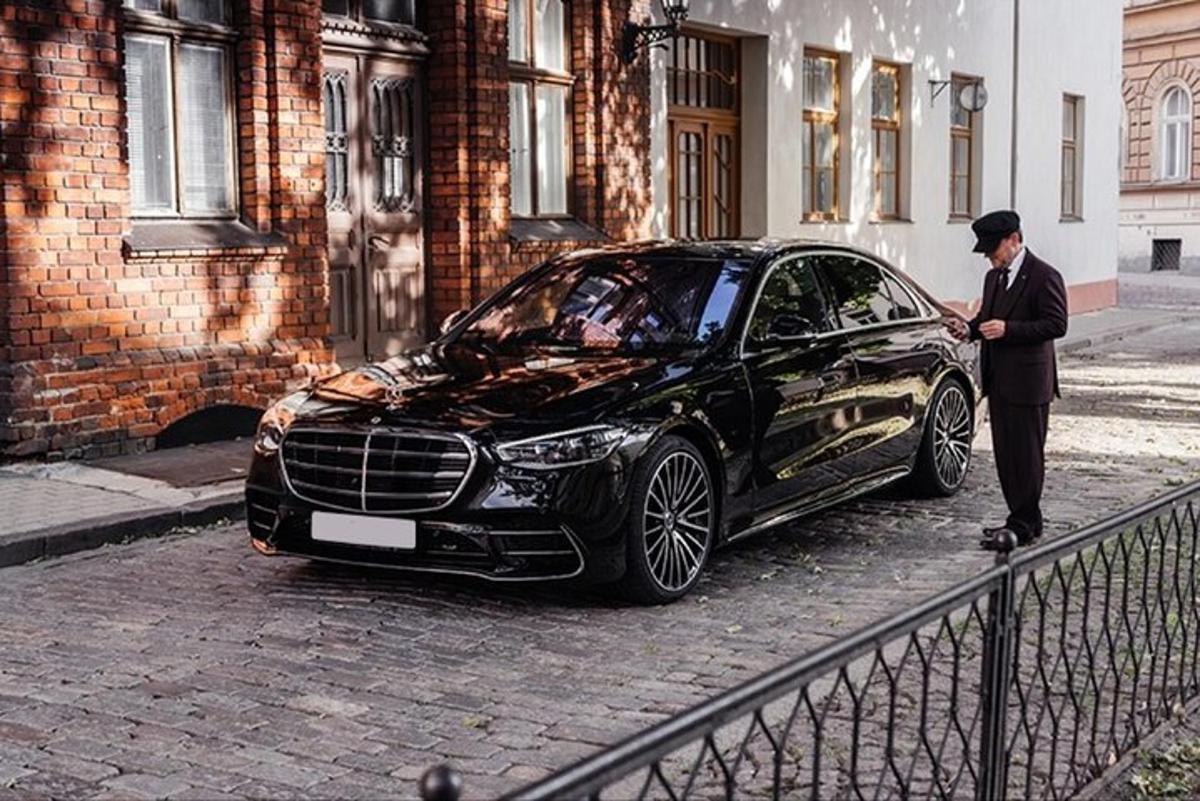 um homem parado ao lado de um carro preto em uma rua