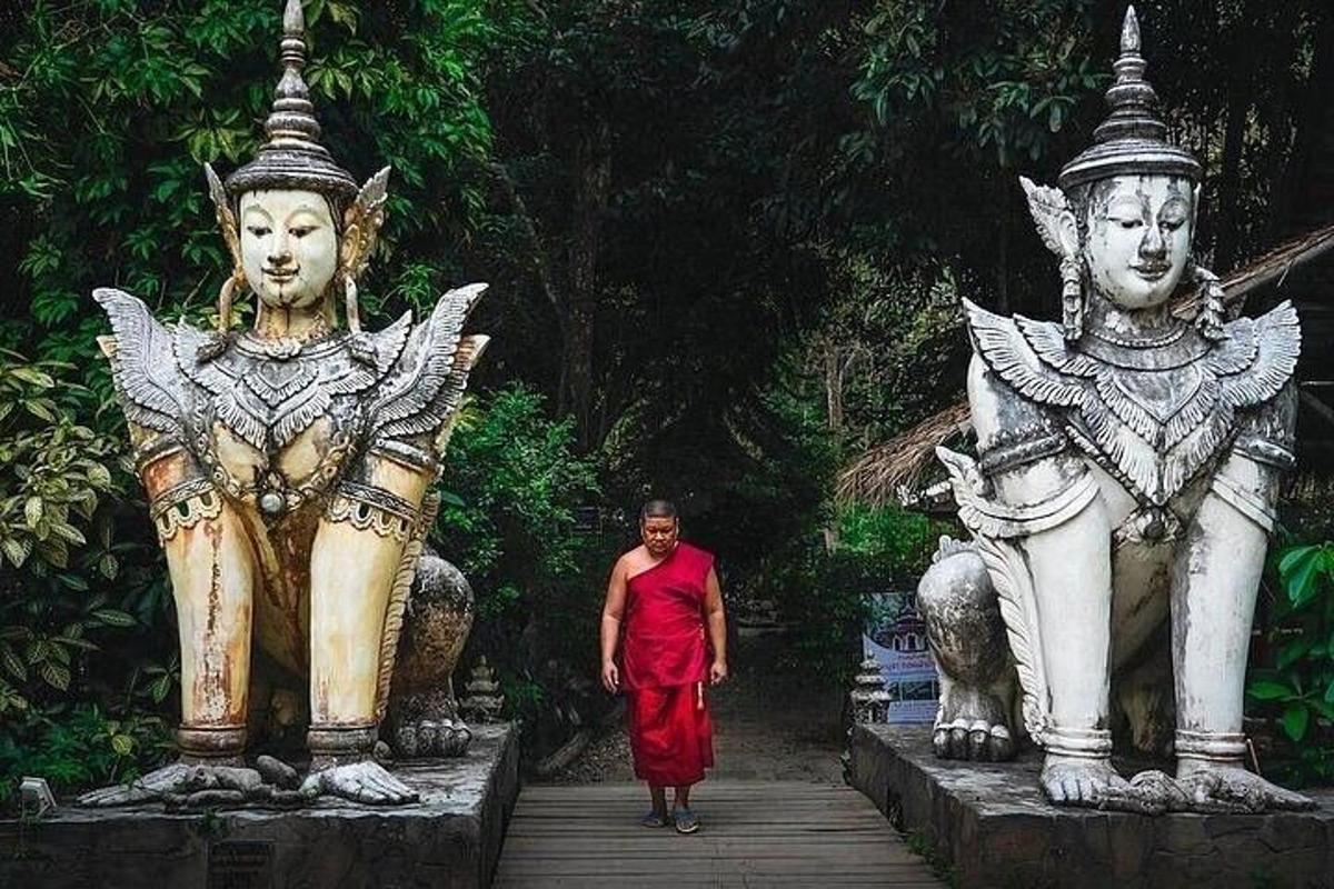 Un hombre con un vestido rojo caminando entre dos estatuas.