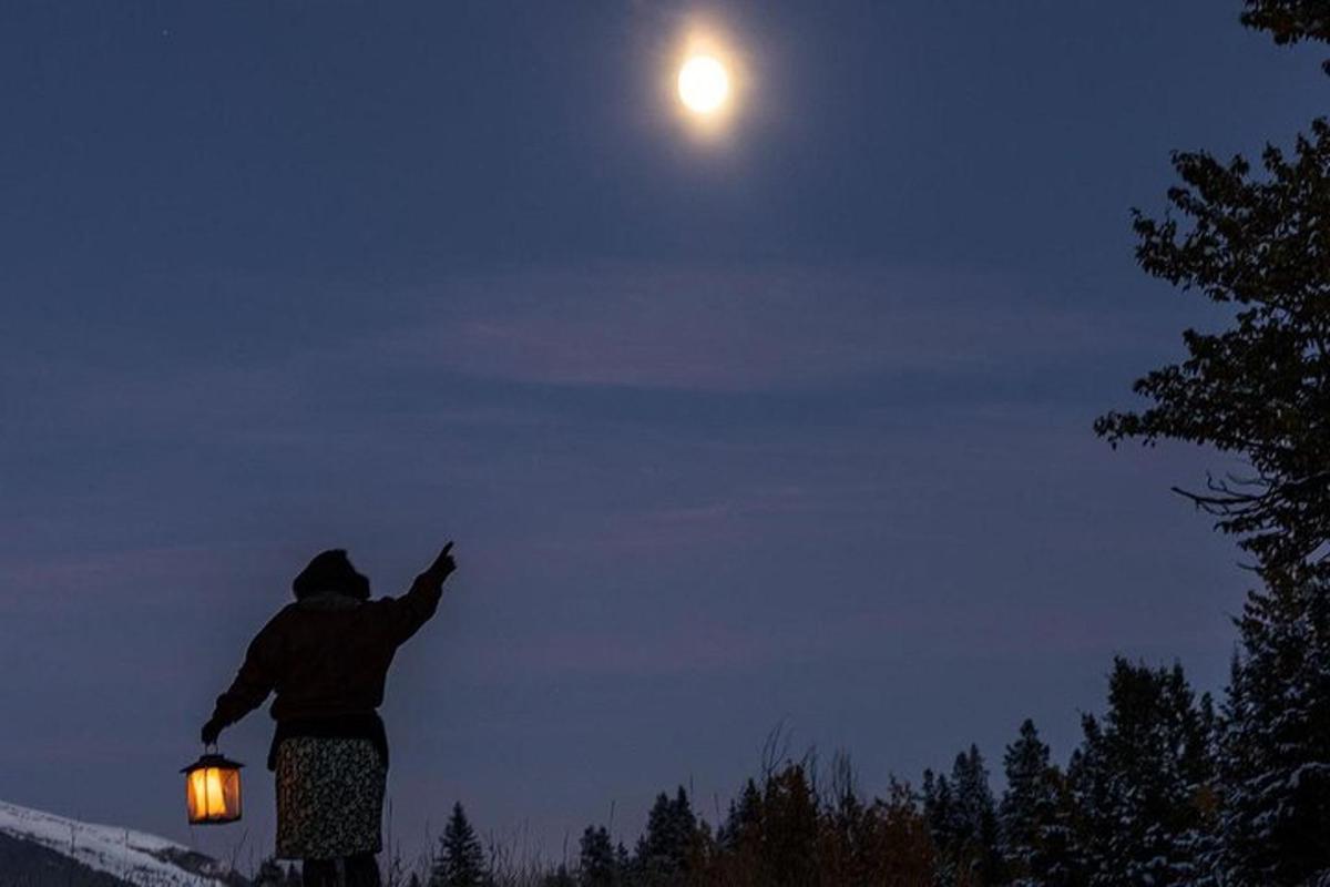 a person pointing at the moon in the sky