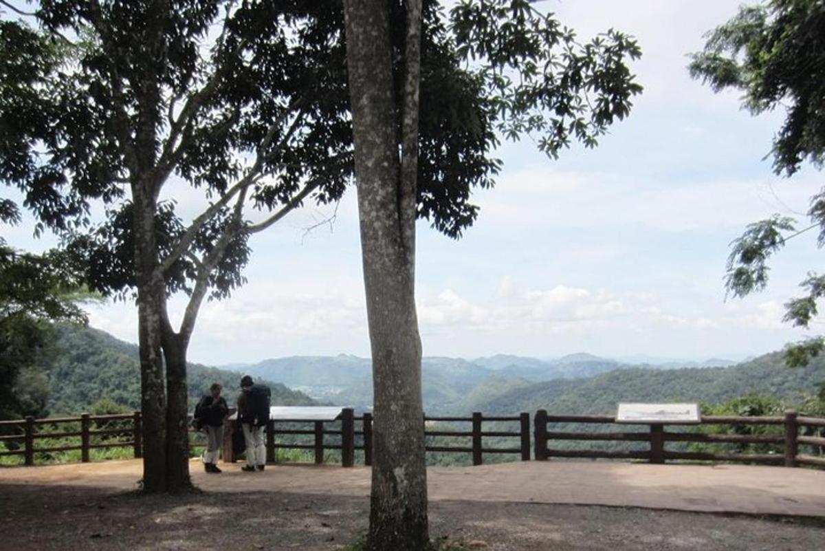 duas pessoas em pé perto de uma cerca olhando para as montanhas