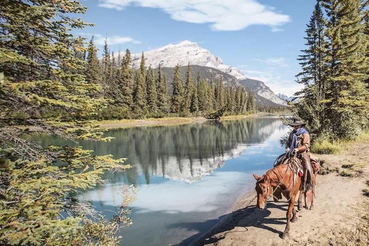 a man riding a horse near a river with a mountain