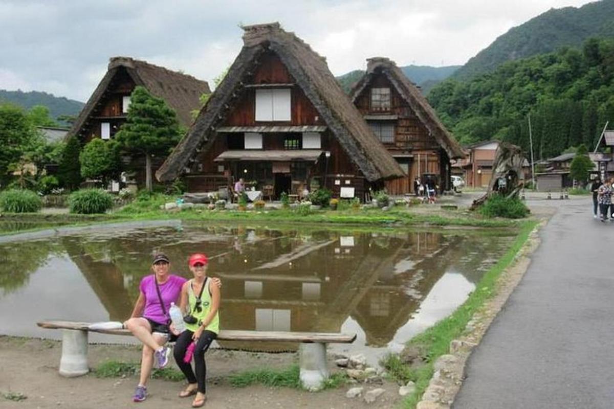 dvě ženy sedící na lavičce před budovou