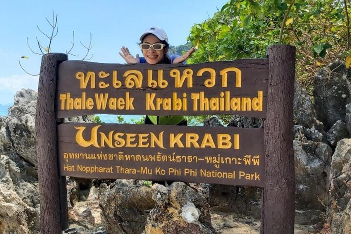 seseorang yang berdiri di belakang papan tanda di pantai