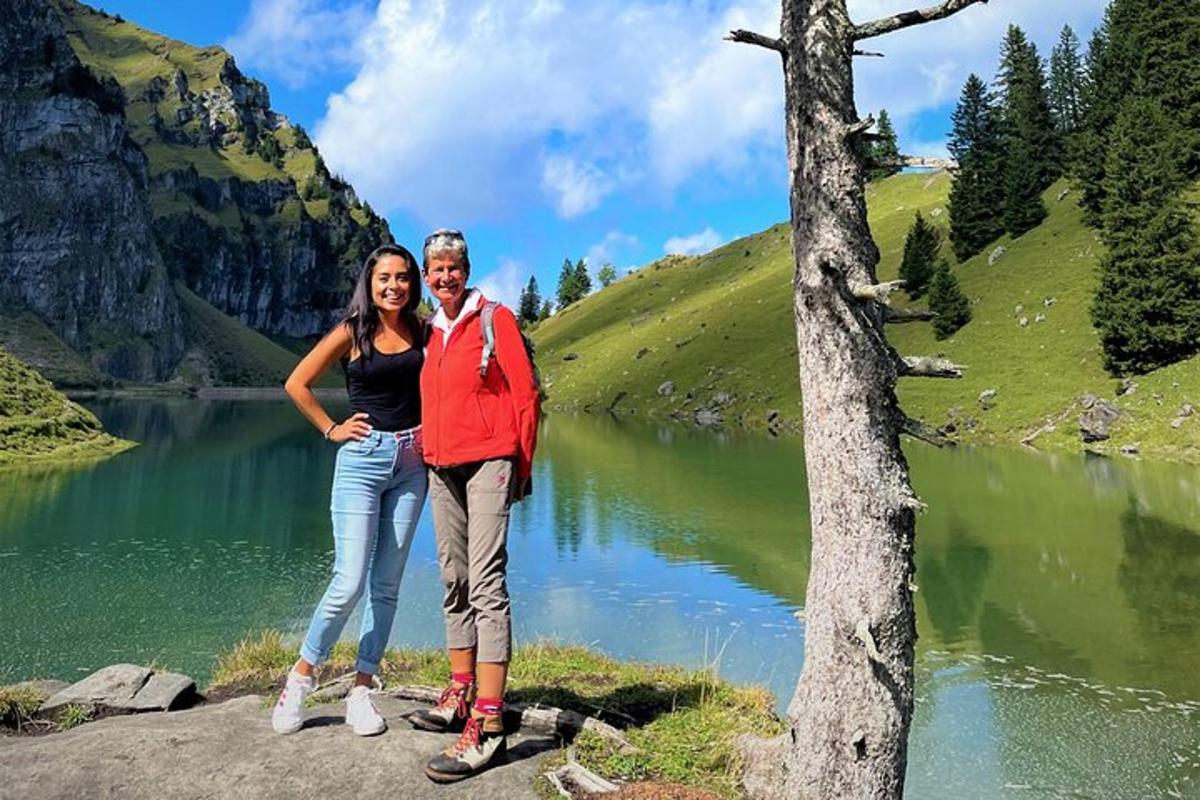 two women standing in front of a mountain lake